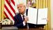 Donald Trump holds a signed executive order in the Oval Office of the White House