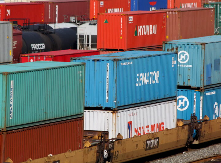 Colourful shipping containers stacked at a rail freight yard, representing cross-border trade