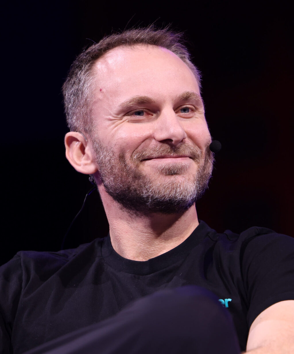 Tether chief executive Paolo Ardoino speaking on stage at a conference, wearing a headset microphone