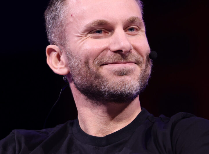 Tether chief executive Paolo Ardoino speaking on stage at a conference, wearing a headset microphone